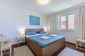 A bedroom with a large bed, bedside tables, a desk, and a window with curtains.
