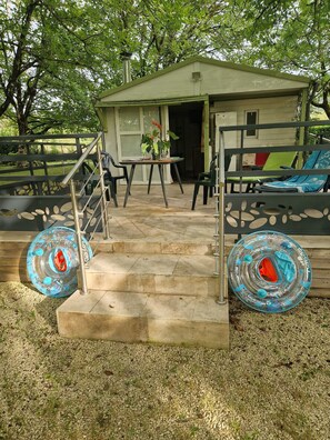 Un petit espace extérieur aménagé avec une table et des chaises, une terrasse couverte et un escalier menant à un bâtiment.