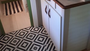 Uma cozinha compacta com micro-ondas, cafeteira e piso estampado.