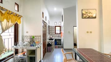 Un estrecho pasillo con una zona de comedor que incluye una mesa y sillas, una cocina con ventana y un salpicadero de azulejos.