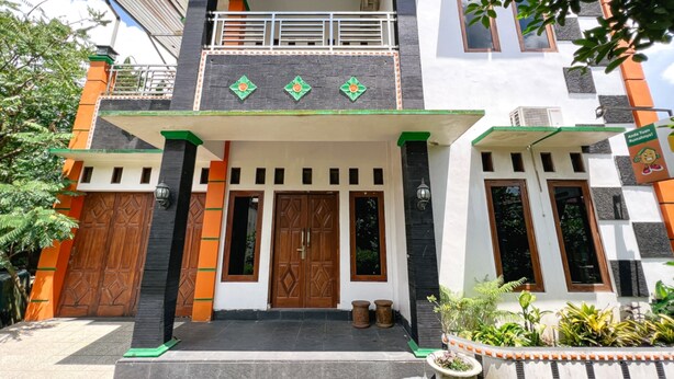 A two-story building with a balcony, large wooden doors, and a tiled entrance. - Homestay Jogja Jakal 3 Dekat UGM by Simply Homy (Ngaglik)