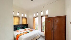 A hotel room with a bed, a wardrobe, and a window with curtains. - Homestay Jogja Jakal 3 Dekat UGM by Simply Homy (Ngaglik)
