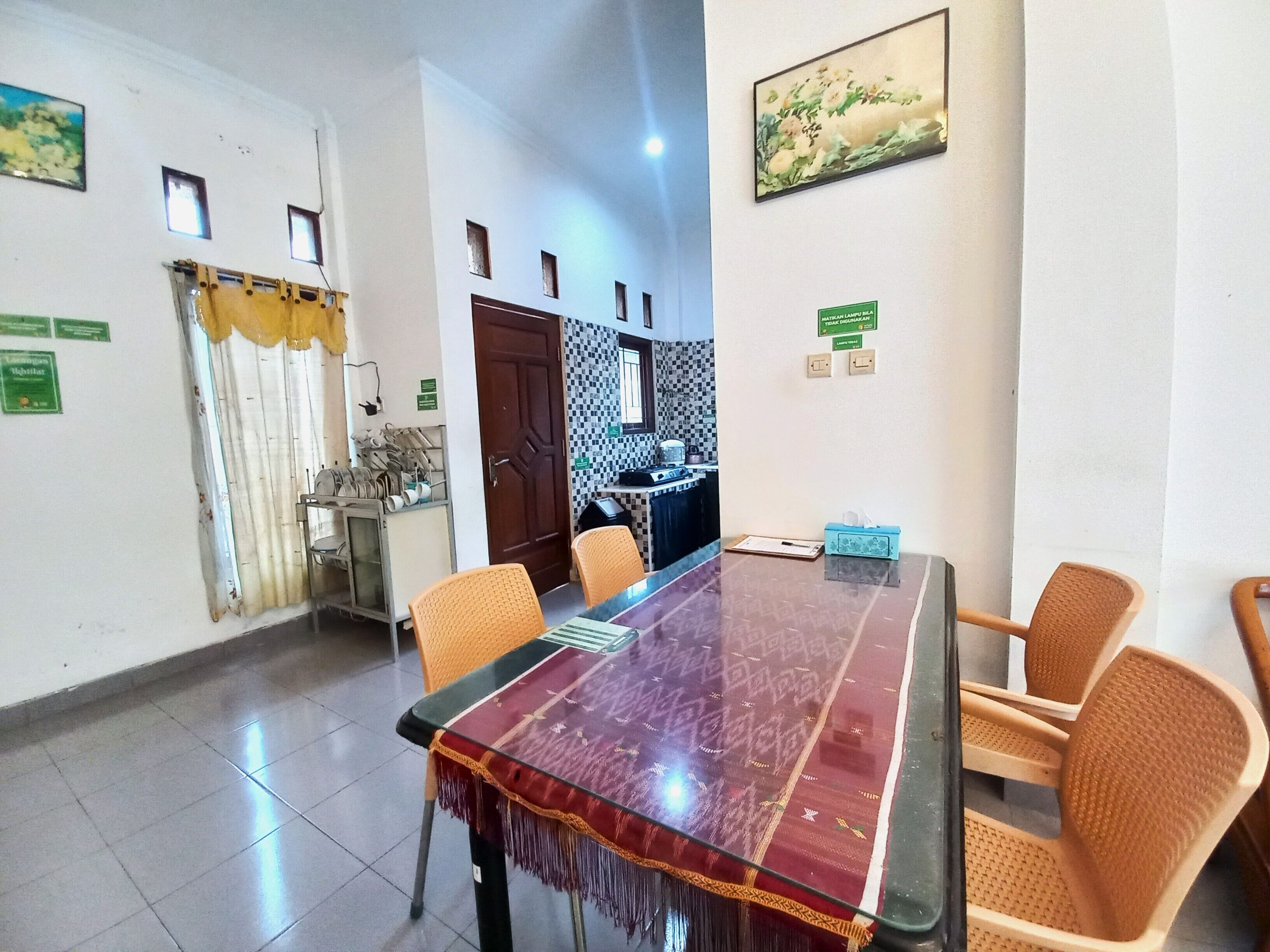 Una sala de conferencias con una mesa de vidrio, sillas anaranjadas, una zona de cocina y una puerta con cortina.