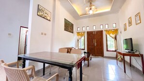 A dining area with a ping pong table, chairs, a television, and a door with a decorative curtain. - Homestay Jogja Jakal 3 Dekat UGM by Simply Homy (Ngaglik)