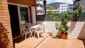 A balcony with a table and chairs, a potted plant, and a view of a hillside. - KESITO FAMILY APARTAMENT BJ.-3ª (Lloret de Mar)