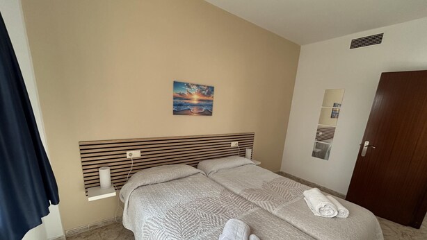 A hotel room with two beds, a painting on the wall, and a door. - KESITO FAMILY APARTAMENT 1ª3ª (Lloret de Mar)
