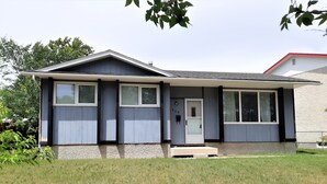 Ein Bungalow mit Veranda, Garage und kleinem Vorgarten.