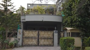 Een hekpoort met daarboven het nummer '2', omringd door groen en een verhard pad dat naar een gebouw leidt.