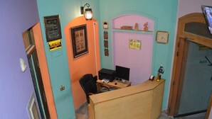 Een klein kantoor met een bureau, computer en stoel. Er hangt een klok aan de muur en is een ingelijst certificaat te zien.