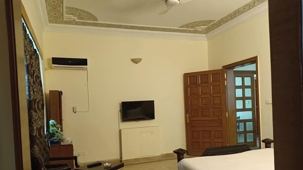 Hotelkamer met een bed, een aan de muur bevestigde televisie, een houten deur en een klein tafeltje met een stoel.