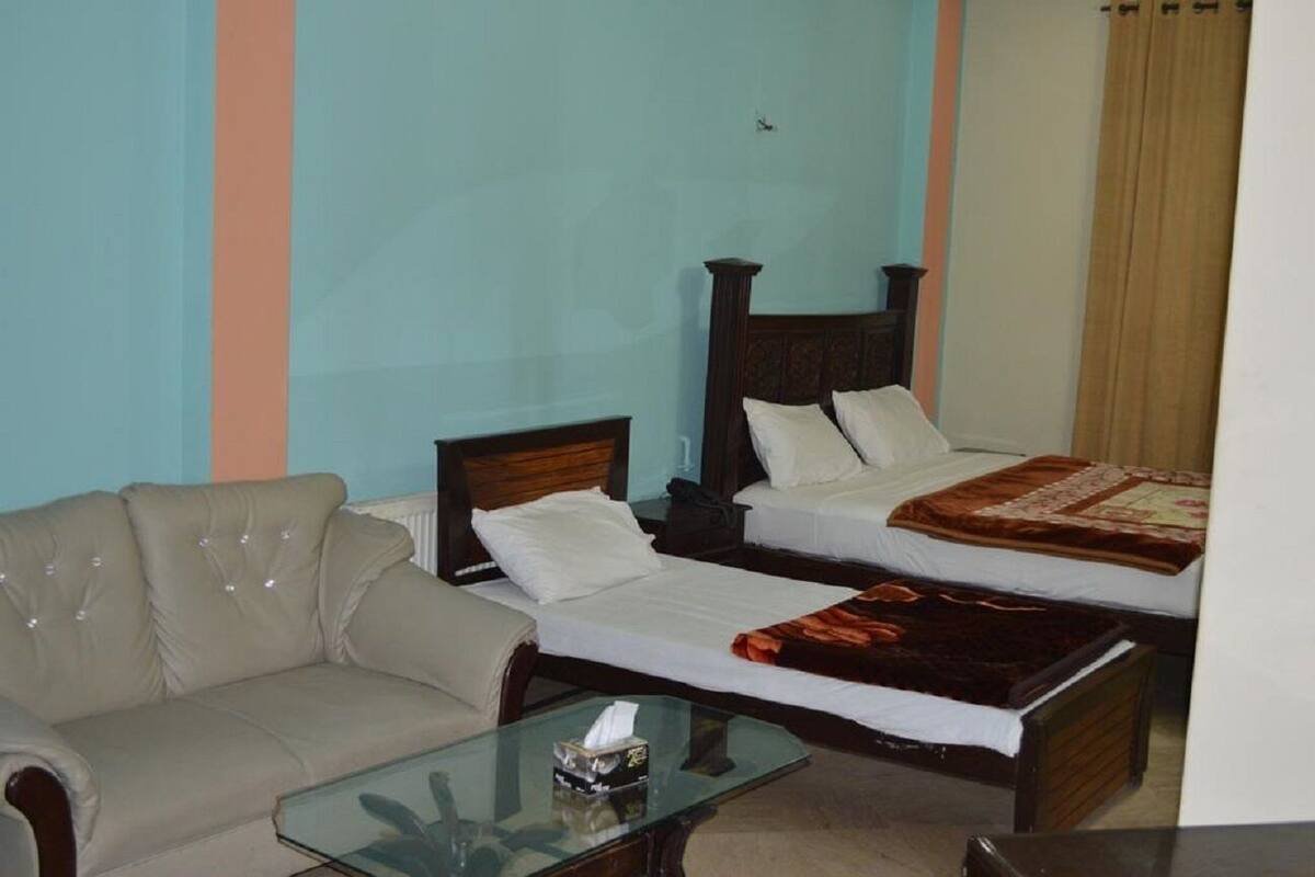 A hotel room with two beds, a sofa, and a glass coffee table.