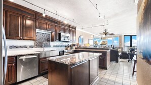 Una cocina amplia con armarios de madera oscura, una isla central, electrodomésticos de acero inoxidable y un ventanal con vistas panorámicas.