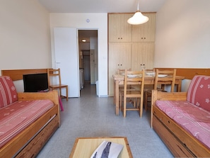 A compact living space with a sofa, a TV, a dining table with chairs, and a kitchenette area. - Cozy apartment near slopes with parking and Wifi (Le Dévoluy)