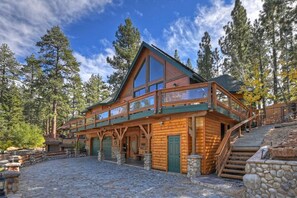 A log cabin with a balcony, stone steps, and a stone wall.