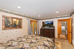 A bedroom with a bed, a dresser, a television, and a painting on the wall. - Luxury in Boulder Bay! Hot Tub! Lake Views! Pool Table! Theater! Air Hockey! (Big Bear Lake)
