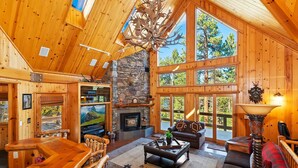 A spacious wooden cabin with a stone fireplace, large windows, and a cozy seating area.