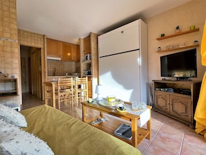 Un espace de vie compact comprenant une kitchenette, un coin repas et un téléviseur.