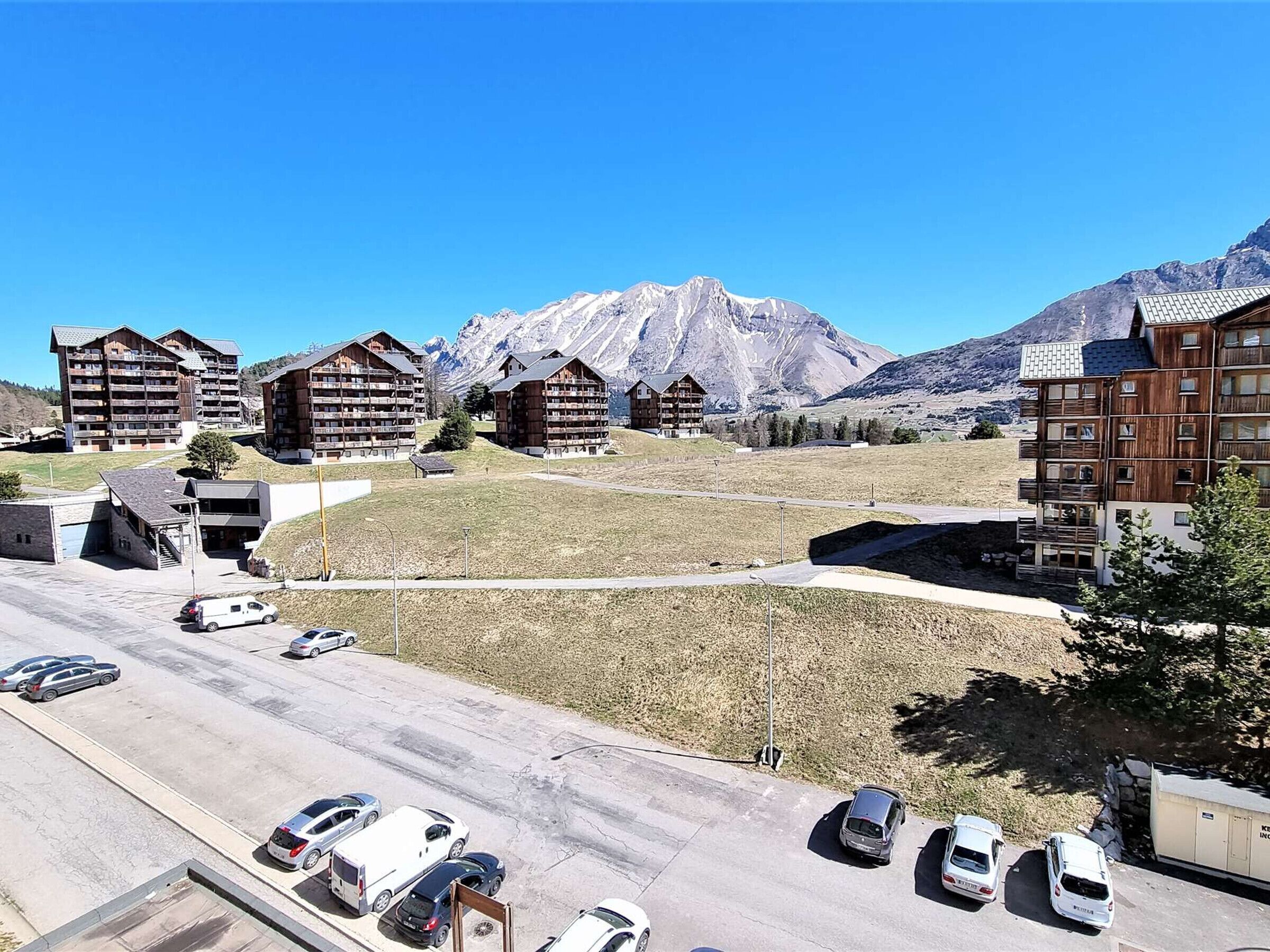 A hotel with multiple wooden buildings, a parking lot with several cars, and a mountain range in the background.
