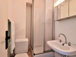 A bathroom with a toilet, a shower enclosure, and a sink.