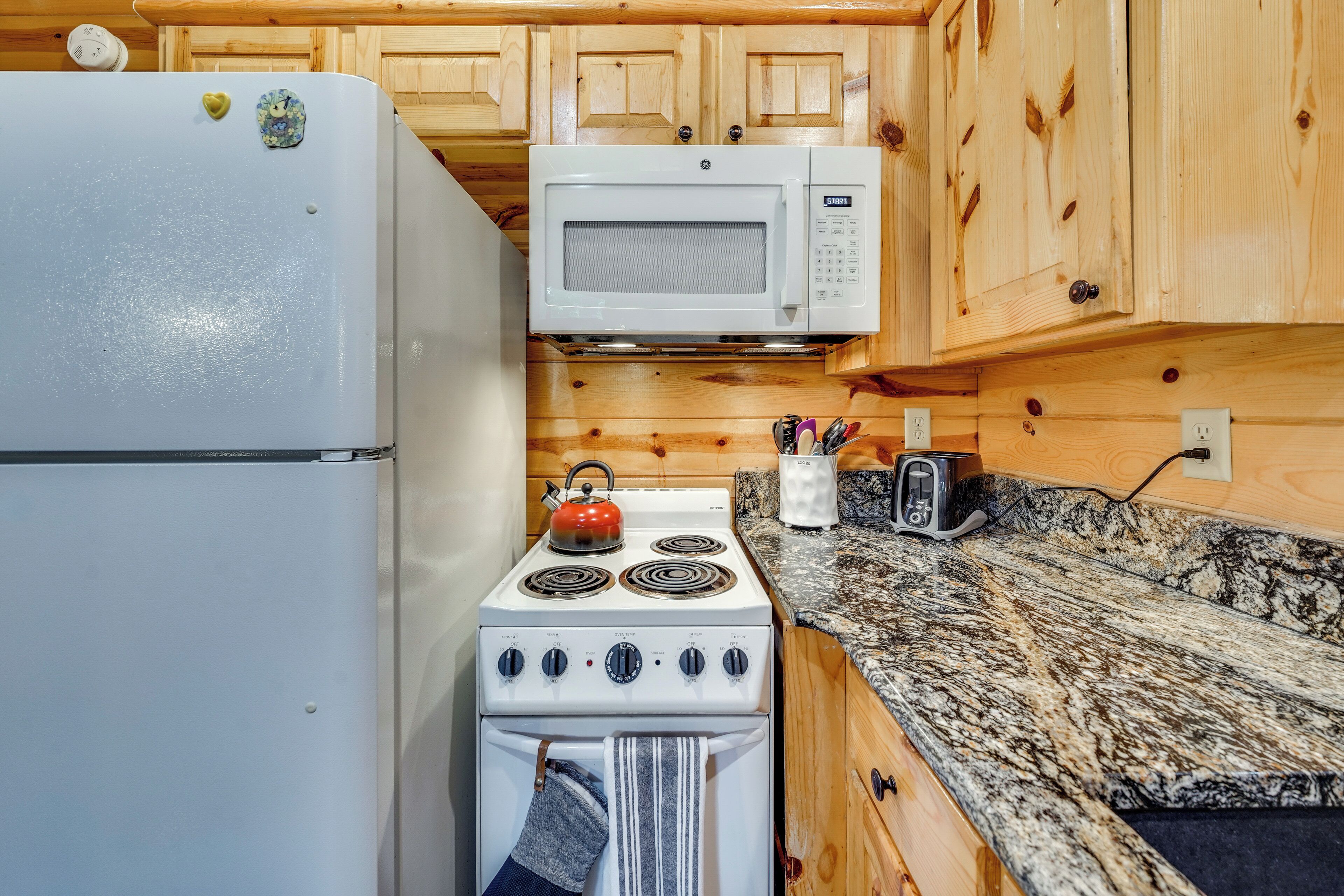 Una cocina con refrigerador blanco, estufa, microondas y armarios de madera.