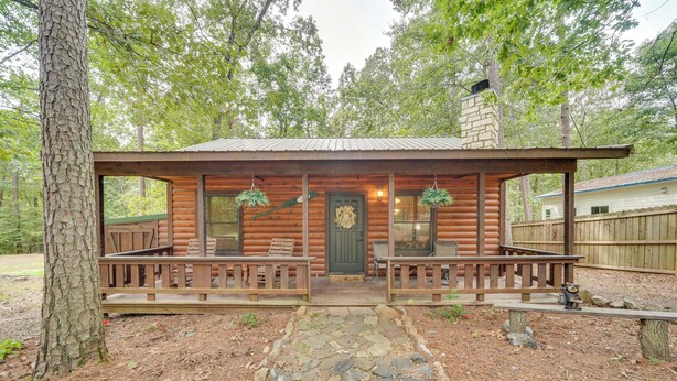 Ein rustikales Blockhaus mit einem Steinweg, der zu einer hölzernen Veranda mit Bänken führt.