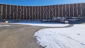 Un grand hôtel à plusieurs étages, doté d’une façade incurvée, d’un parking et d’un petit bâtiment situé à l’avant.