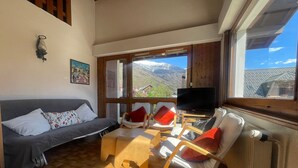 A cozy living room with a sofa, chairs, a TV, and a view of mountains. - Family duplex in village center, pets allowed (Samoëns)