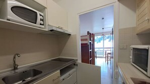 A compact kitchen with a built-in microwave, a sink, and a refrigerator.