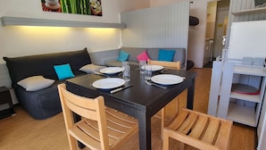 Un comedor con una mesa negra, sillas de madera y un sofá gris con cojines.