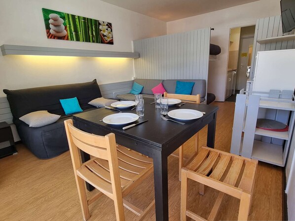 A dining area with a black table, wooden chairs, and a grey sofa with cushions. - Cozy studio near slopes with Wifi, parking and pets allowed (Le Dévoluy)