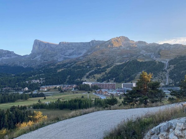 A mountainous landscape with a road leading to a cluster of buildings, likely a hotel or resort.
