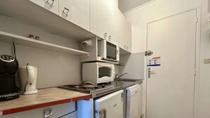 A compact kitchen with a microwave, stove, and coffee maker.