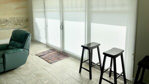Une pièce avec un canapé vert, deux tabourets noirs et un tapis à motifs.