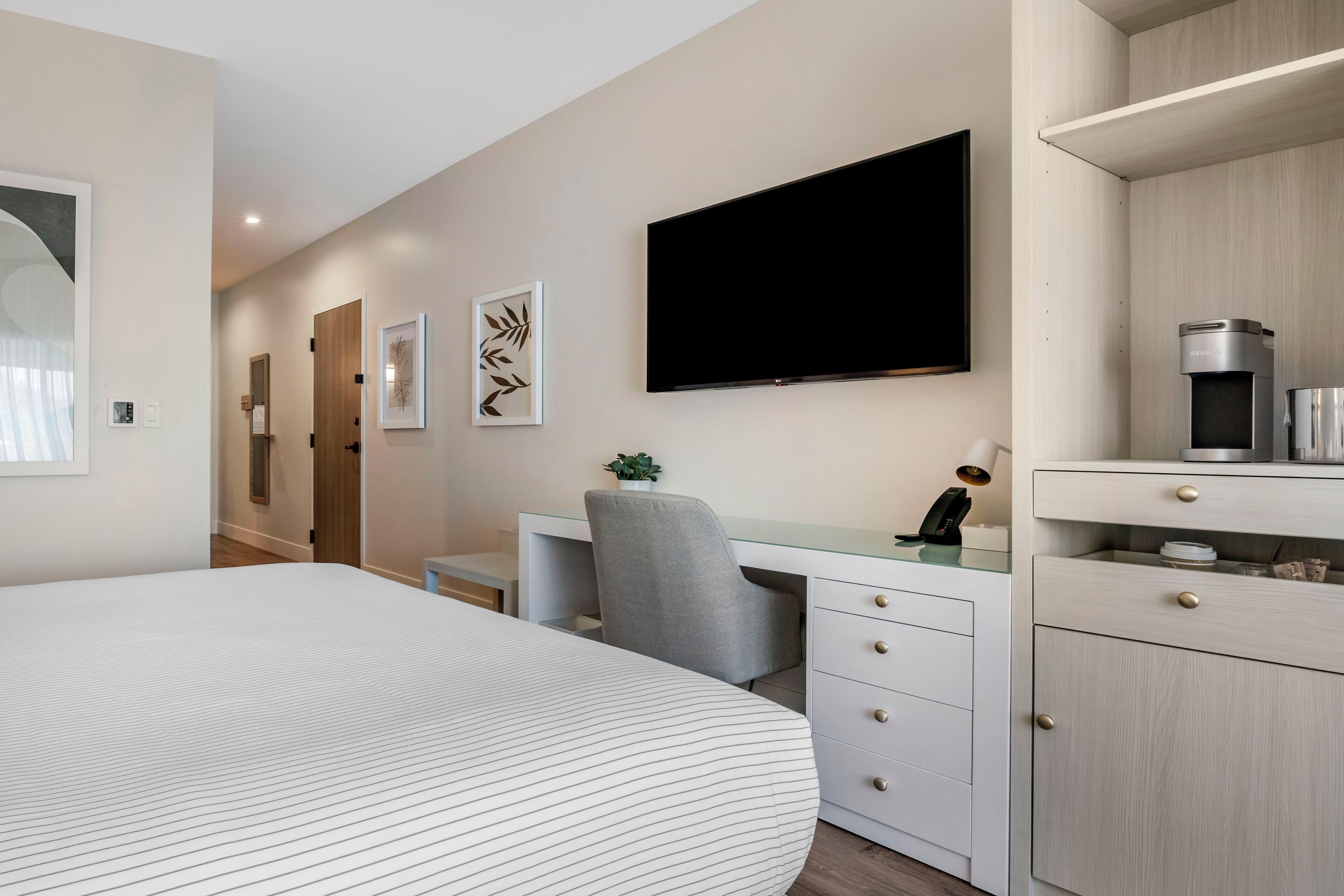 Une chambre d’hôtel moderne dotée d’un grand lit, d’un bureau avec une chaise, d’une télévision à écran plat et d’un mini-bar.