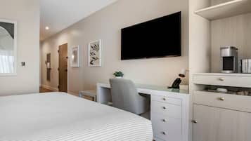 Une chambre d’hôtel moderne dotée d’un grand lit, d’un bureau avec une chaise, d’une télévision à écran plat et d’un mini-bar.
