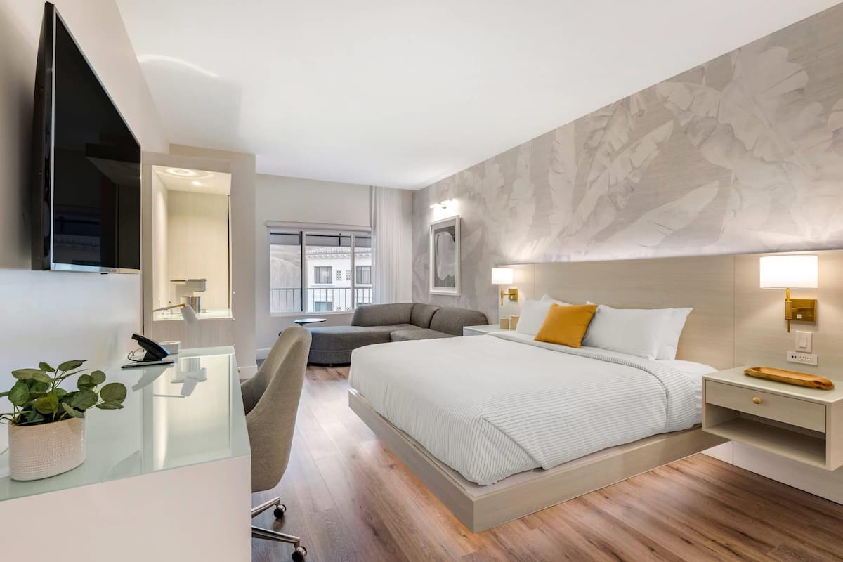 Una habitación de hotel moderna con una cama grande, un escritorio con una silla, un sofá y un televisor.