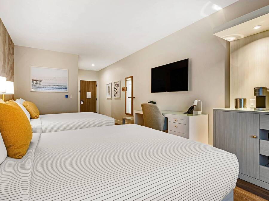 Habitación de hotel con dos camas, un escritorio, una silla, un televisor de pantalla plana y un minibar.