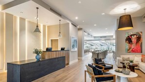 A modern hotel lobby with a reception desk, seating area, and a view of the outdoor terrace. - Cambria Hotel Calabasas - Malibu (Calabasas)