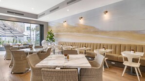 Un comedor moderno con una mesa larga, sillas de mimbre y un sofá beige.