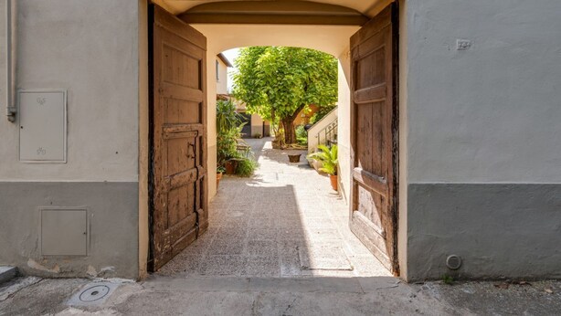 An arched doorway leading to a courtyard with a tree, potted plants, and a stone pathway. - GuestHost - Cozy 50 sqm apartment, able to accommodate up to 5 people, located on the ground floor (1 low step to access to it) of a farmhouse surrounded by greenery, a short distance from the center of Florence. The property is located a few meters from (Firenze)