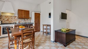 A compact kitchen with a dining table, wooden cabinets, and a TV mounted on the wall. - GuestHost - Cozy 50 sqm apartment, able to accommodate up to 5 people, located on the ground floor (1 low step to access to it) of a farmhouse surrounded by greenery, a short distance from the center of Florence. The property is located a few meters from (Firenze)
