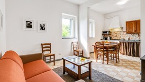 A living room with a sofa, chairs, a coffee table, and a kitchen area with a dining table and chairs. - GuestHost - Cozy 50 sqm apartment, able to accommodate up to 5 people, located on the ground floor (1 low step to access to it) of a farmhouse surrounded by greenery, a short distance from the center of Florence. The property is located a few meters from (Firenze)