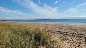 A beach with sand and sparse vegetation. - Charming 2-bedroom cottage in Old Orchard Beach, perfect for family getaways. (Old Orchard Beach)
