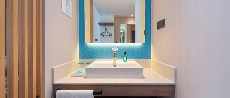 A modern bathroom with a white sink, a mirror with a blue accent, and a towel rack.