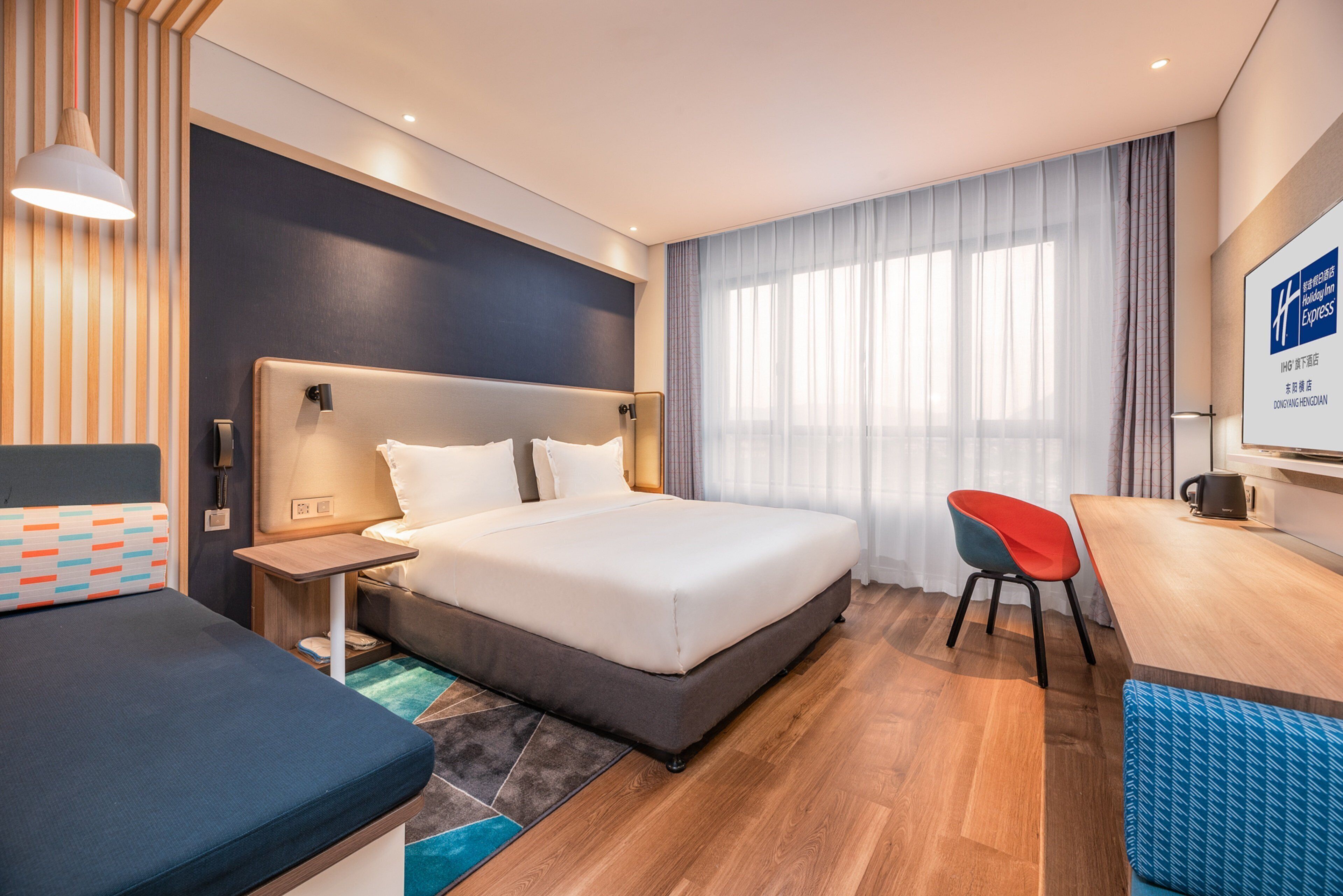 Una habitación de hotel moderna con una cama grande, un escritorio y una silla.