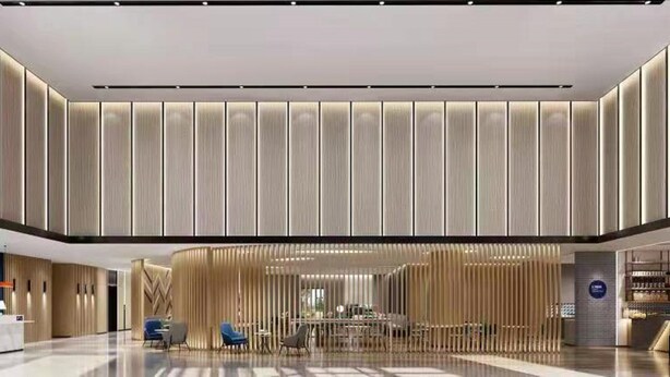 Eine moderne Hotelhalle mit einer zentralen Sitzgruppe, einem Empfangstresen und einer Treppe zu den oberen Etagen.