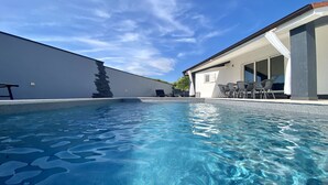 A swimming pool with clear blue water, surrounded by a white wall and a building with a modern design. - Stunning 3-bedroom Villa With a Private Pool-pula (Pula)
