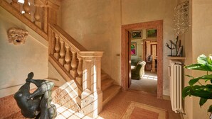 A grand staircase with ornate balusters, a radiator, and a decorative mask on the wall. - Villa Torre di Terzolan With Pool and Jacuzzi (Verona)