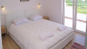 A bedroom with a large bed, two bedside tables, a nightstand, a window with a view of greenery, and a painting on the wall. - A1 - Modern apt With Balcony, sea View & Parking (Sucuraj)
