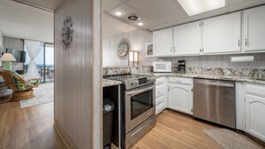 Une cuisine moderne avec des armoires blanches, des appareils en acier inoxydable et un plancher en bois.